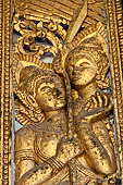 Wat Xieng Thong temple in Luang Prabang, Laos. Detail of a wooden door of the sim with gilded carvings on a red background. 